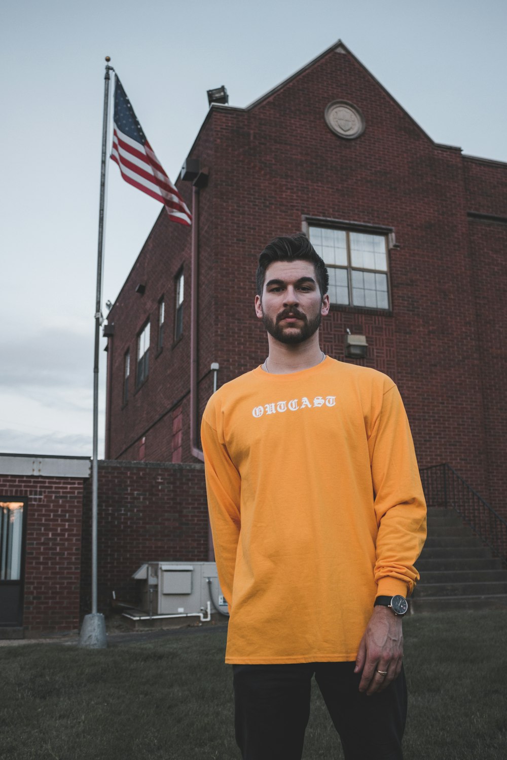 man in yellow Chicago long-sleeved shirt standing near post with American Flag