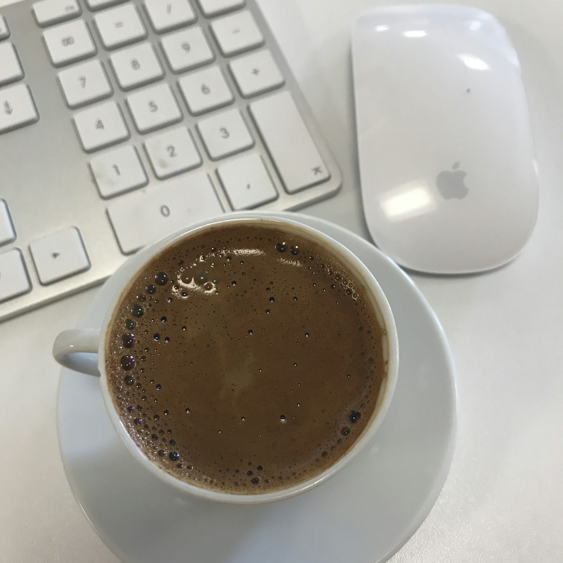 Close-up of hands typing on a keyboard with a cup of coffee nearby, set against a white background with blue and gold accents.