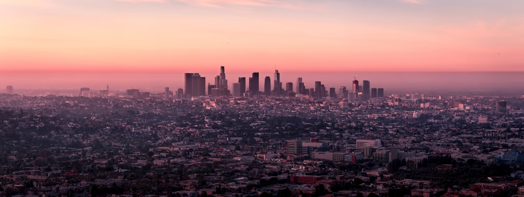 landscape photo of city buildings during dusk, After a long flight from Europe, I woke up at around 3am local time and searched for what to do… I found a trail to hike from just north of Hollywood to the Griffith Observatory. An incredible experience as the sun rose over the city of millions. Good morning and a good Friday to all!