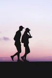 silhouette photo of man and woman wearing caps