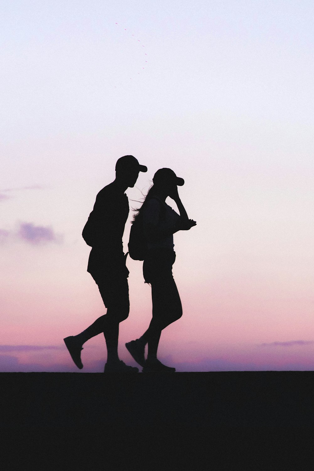 Foto de la silueta del hombre y la mujer con gorras