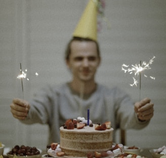 selective focus photography of man holding sparklers between cake