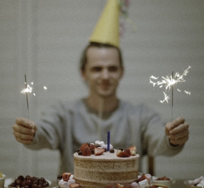 selective focus photography of man holding sparklers between cake