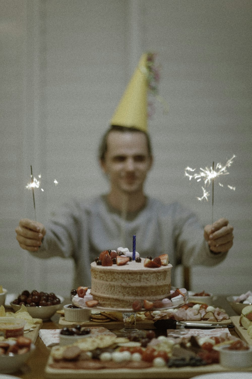 ケーキの間に線香花火を持つ男性のセレクティブフォーカス写真