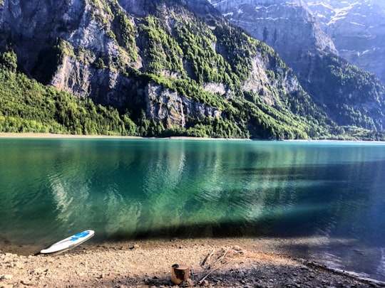white boat on shore near green mountain in Klöntalersee Switzerland