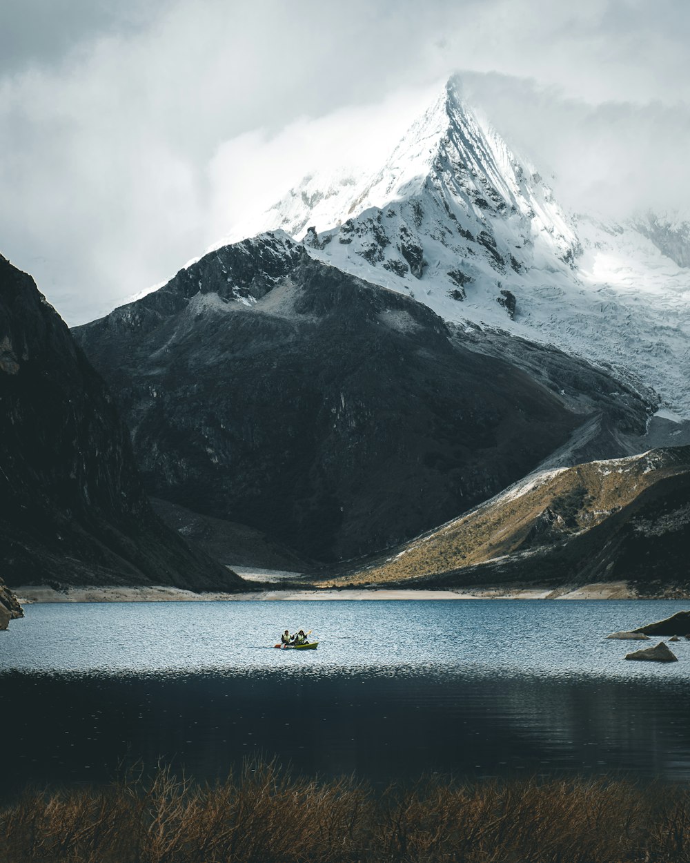 sail boat on body of water beside mountain with snow