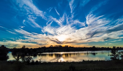 A serene landscape photo capturing the soft glow of sunset light over a quiet lake.