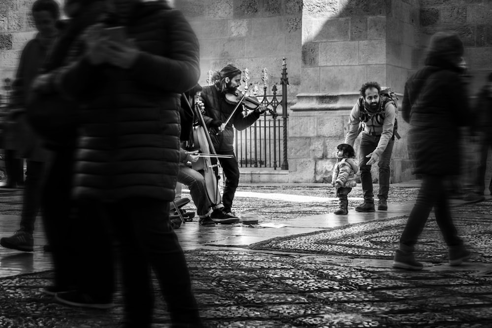 Ragazza in scala di grigi che guarda gli uomini che suonano gli strumenti