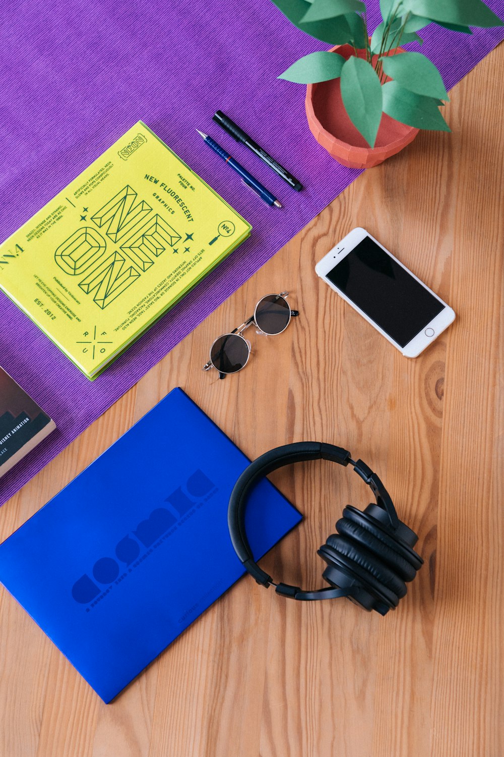 headphones near sunglasses, iPhone 6, and pens on wooden surface