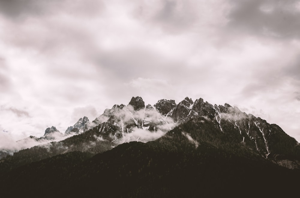 grayscale photography of mountain under cloudy sky