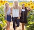 three women standing between sunflowers