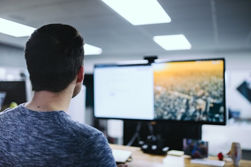 man sitting in front computer monitor