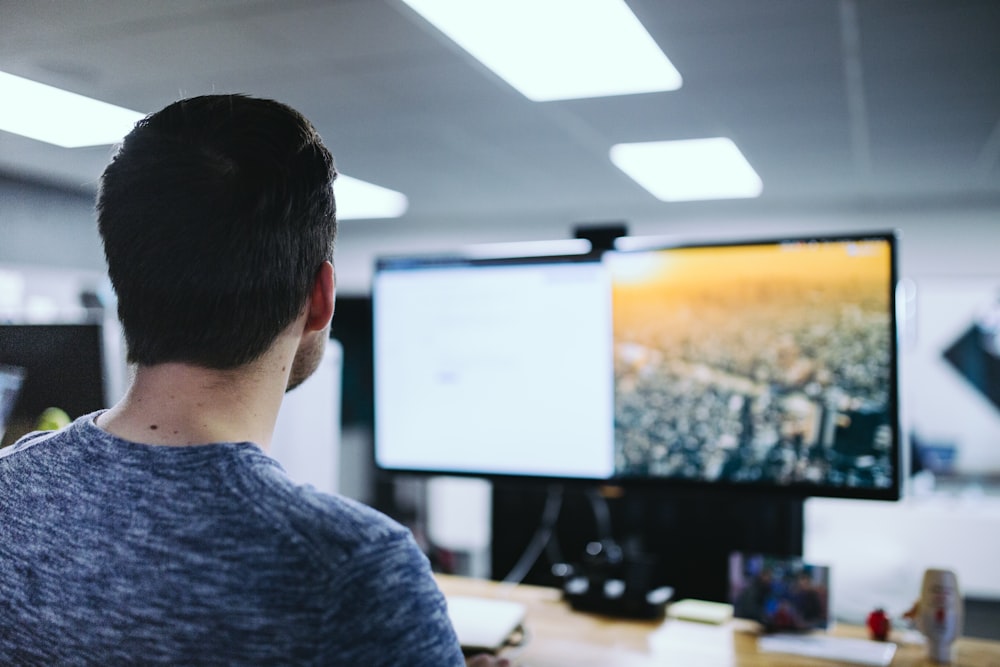 man sitting in front computer monitor