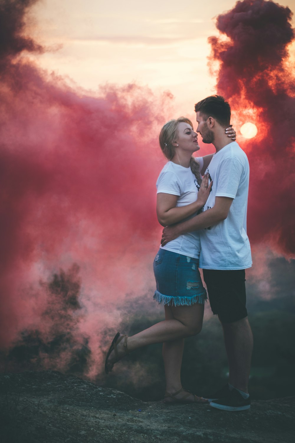 man and woman about to kiss with pink smoke background
