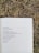 An open book lies on dry grass, displaying a poem with emotional and somber imagery about little girls and devastation.