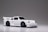 A small, detailed model car with a sleek white finish and prominent black detailing. The car features a spoiler, black wheels, and intricate headlight designs.