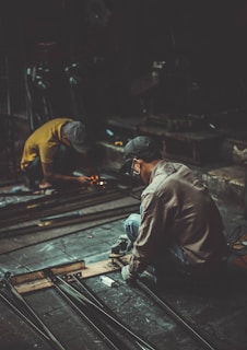 man holding angle grinder and metal rod