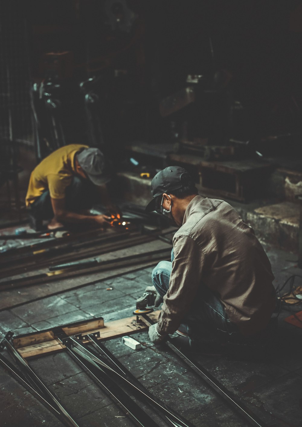 man holding angle grinder and metal rod