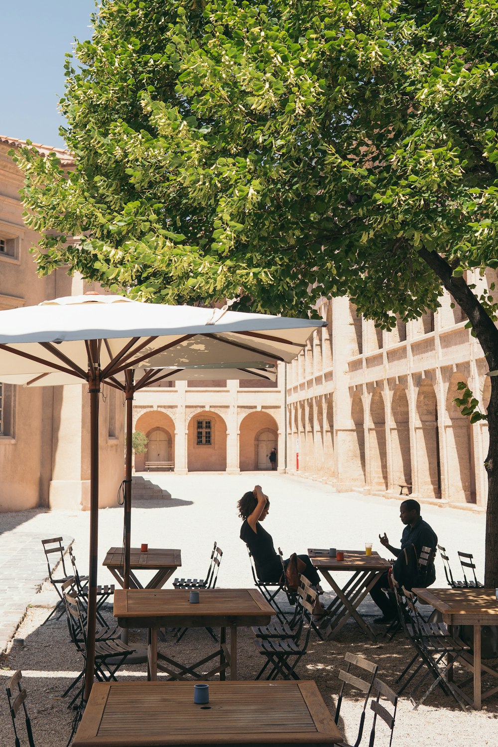 man and woman sitting on chair while dining under patio umbrella