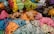 A collection of colorful cords and ropes neatly piled together. There are various shades of green, yellow, pink, blue, and brown, creating a vibrant and diverse palette of colors and textures. The arrangement showcases different sizes and thicknesses of the cords.