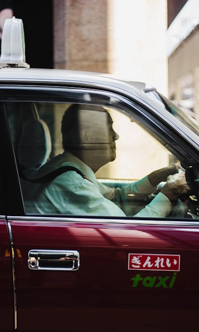 A friendly taxi driver helping a passenger into a clean, spacious taxi.