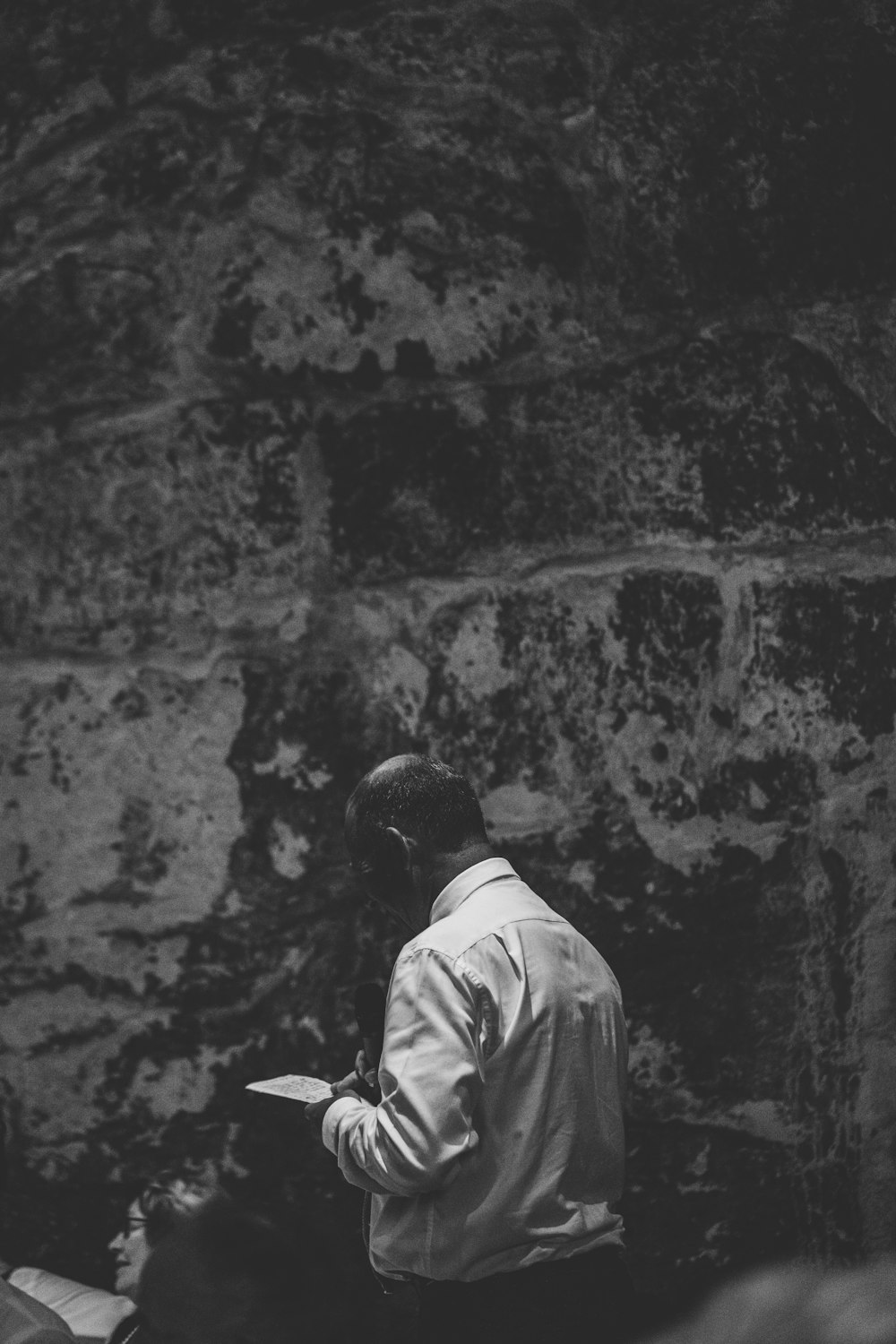 grayscale photography of man walking beside wall