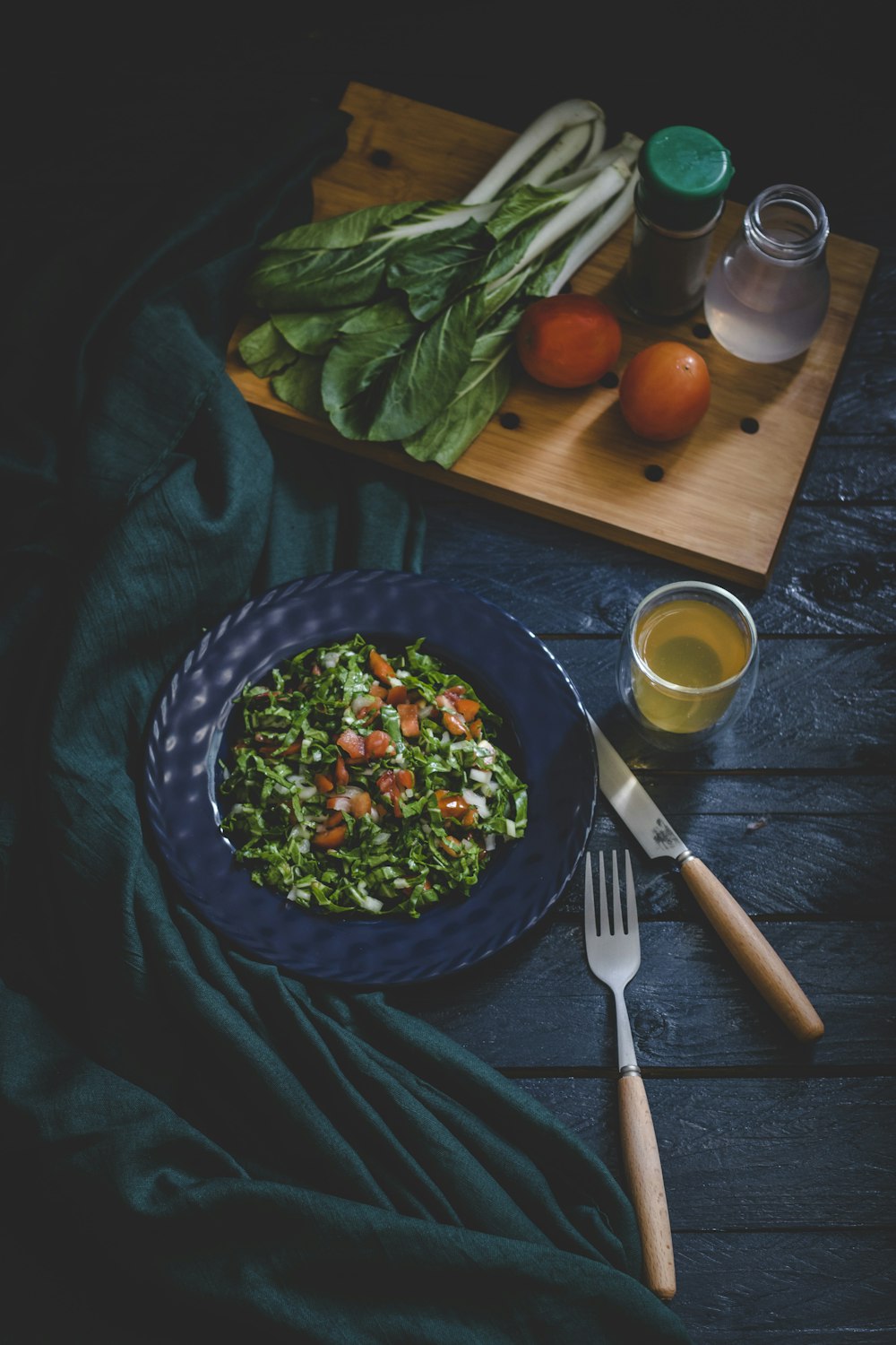 Ensalada de verduras en un bol con tenedor, cuchillo y vaso