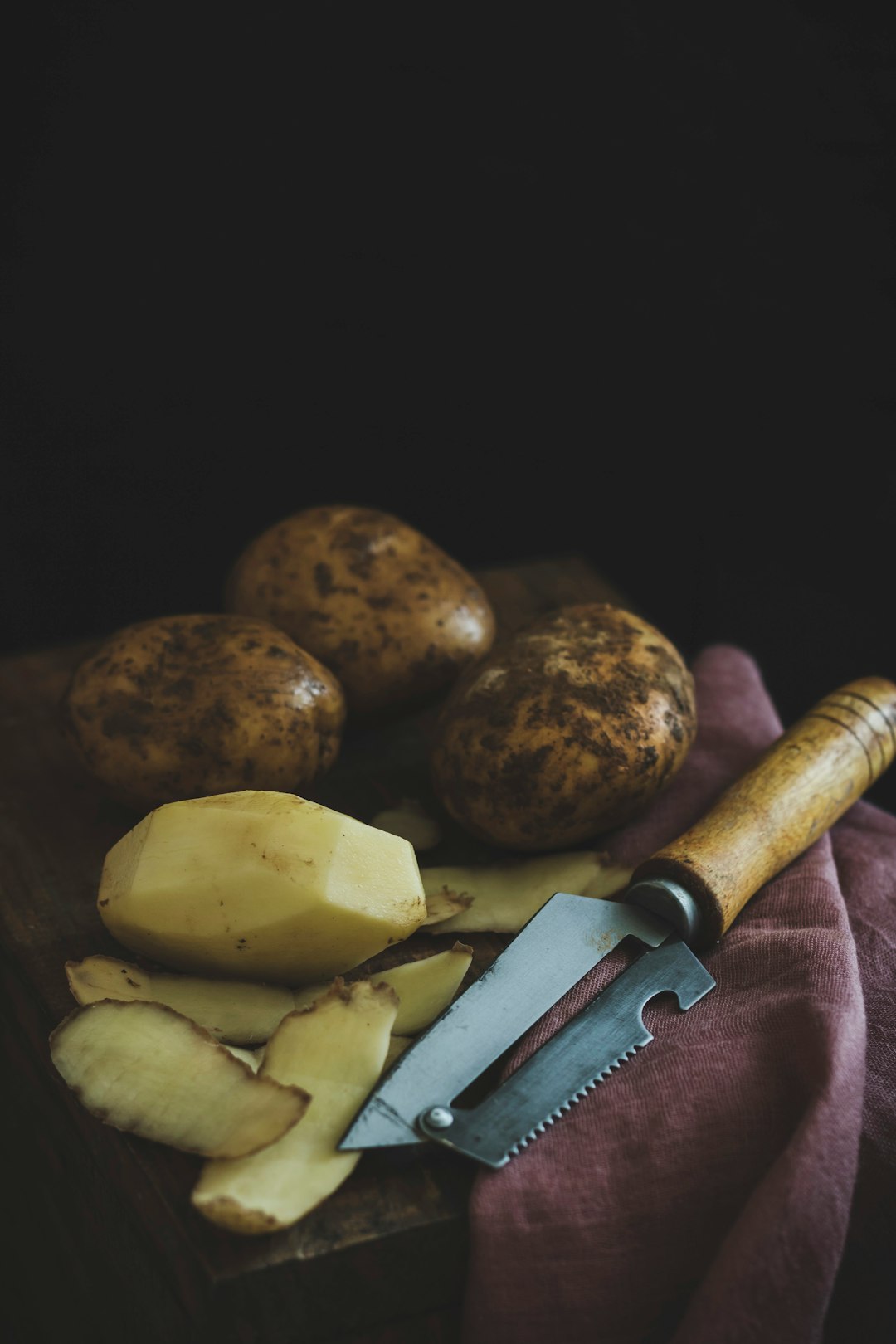 peeled and unpeeled potatoes on top of wooden table