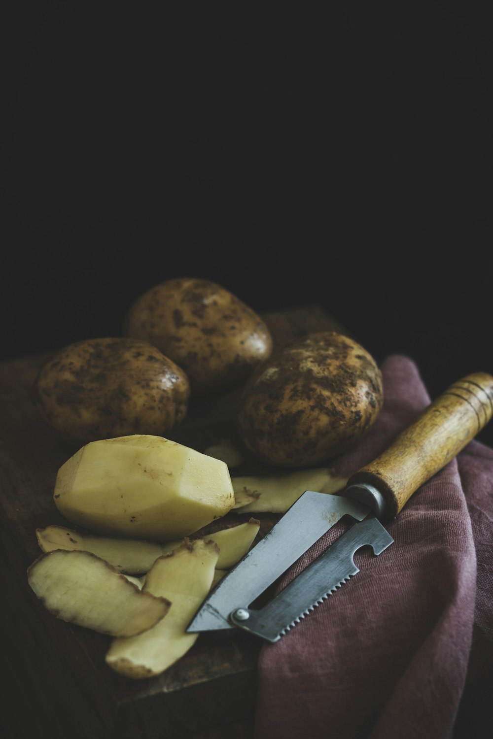 geschälte und ungeschälte Kartoffeln auf Holztisch