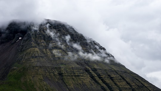 brown mountain with smoke in Ísafjörður Iceland