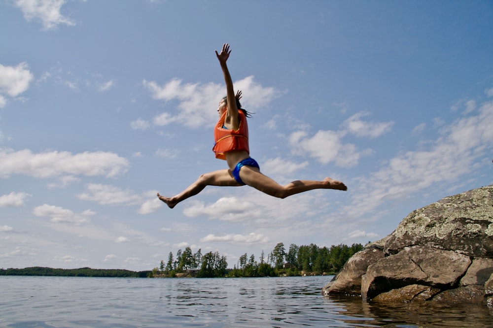 woman jumping towards water wearing life vest