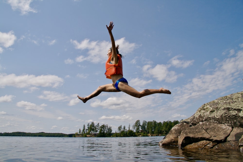Mujer saltando hacia el agua con chaleco salvavidas