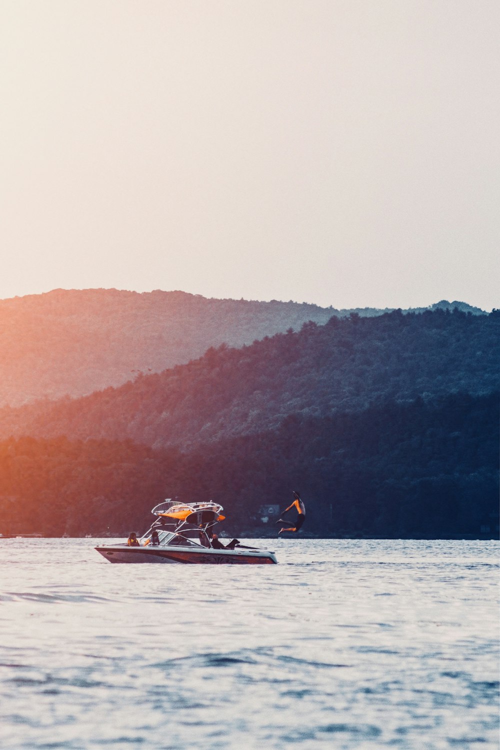 person jumping on water from boat