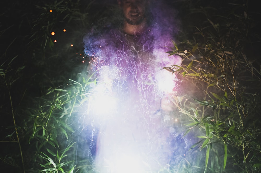 man standing between green plants