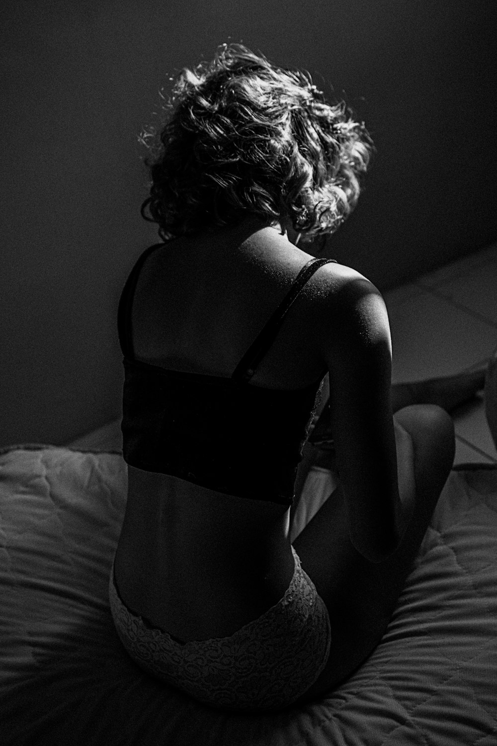 Graustufenfoto einer Frau, die auf dem Bett sitzt