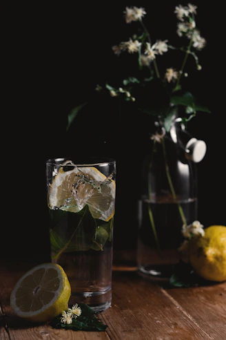 clear drinking glass and sliced lemons on wooden surface