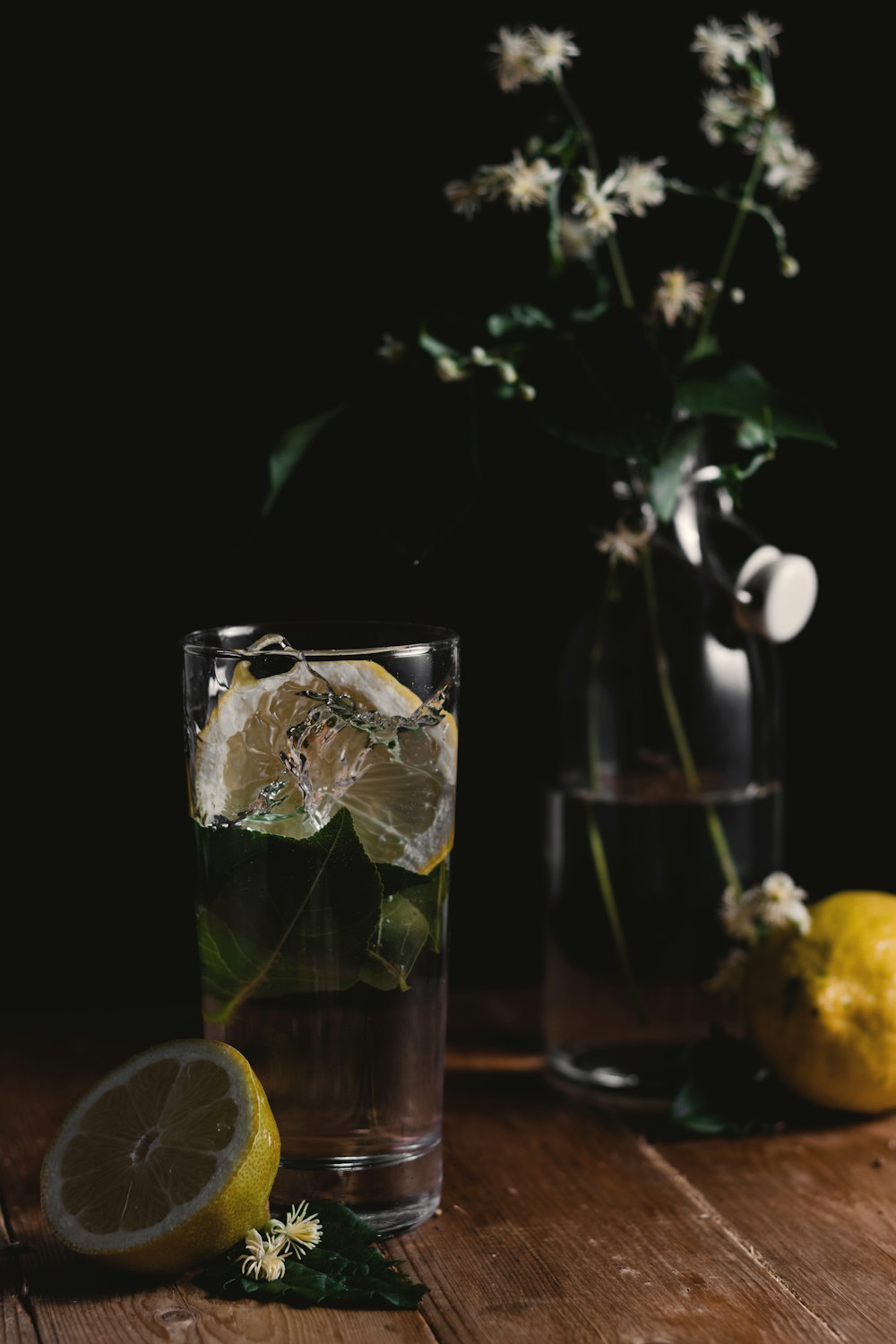 clear drinking glass and sliced lemons on wooden surface