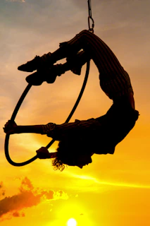 A powerful silhouette of a woman stretching on aerial hoop with dramatic lighting highlighting her form