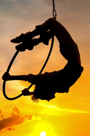 Close-up of hands gripping aerial hoop with golden sunlight streaming in.