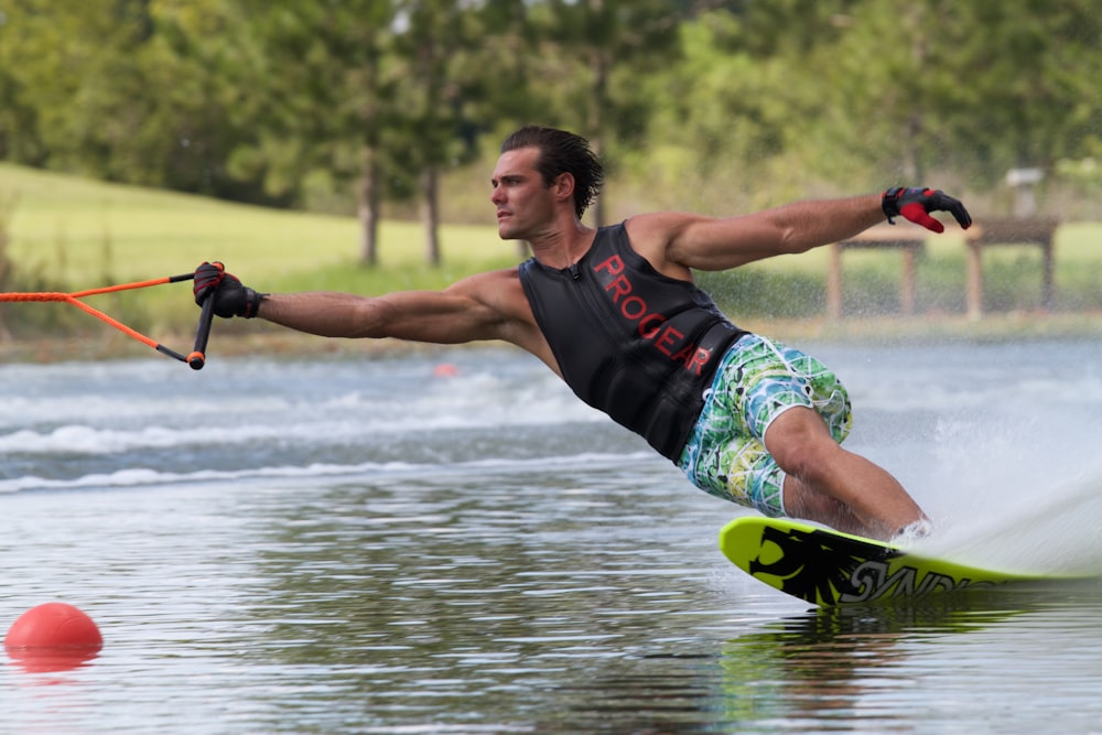 Hombre con guantes y camiseta sin mangas negra mientras practica esquí acuático