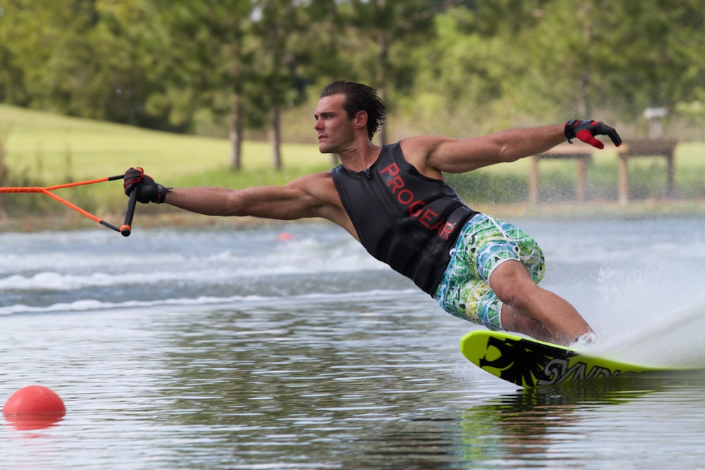 Mann mit Handschuhen und schwarzem Tanktop beim Wasserski