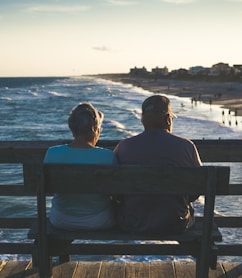 man and woman sitting on bench in front of beach