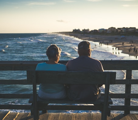 man and woman sitting on bench in front of beach