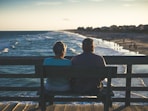 man and woman sitting on bench in front of beach
