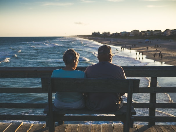 man and woman sitting on bench in front of beach