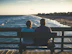 man and woman sitting on bench in front of beach