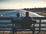 man and woman sitting on bench in front of beach