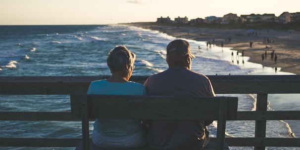 man and woman sitting on bench in front of beach