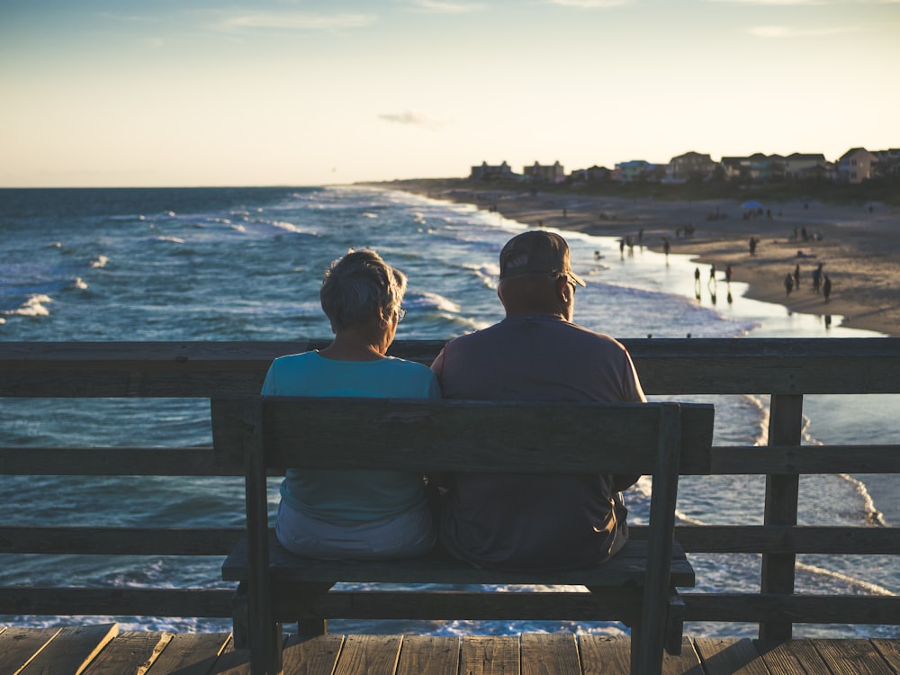 Mann und Frau sitzen auf Bank vor dem Strand