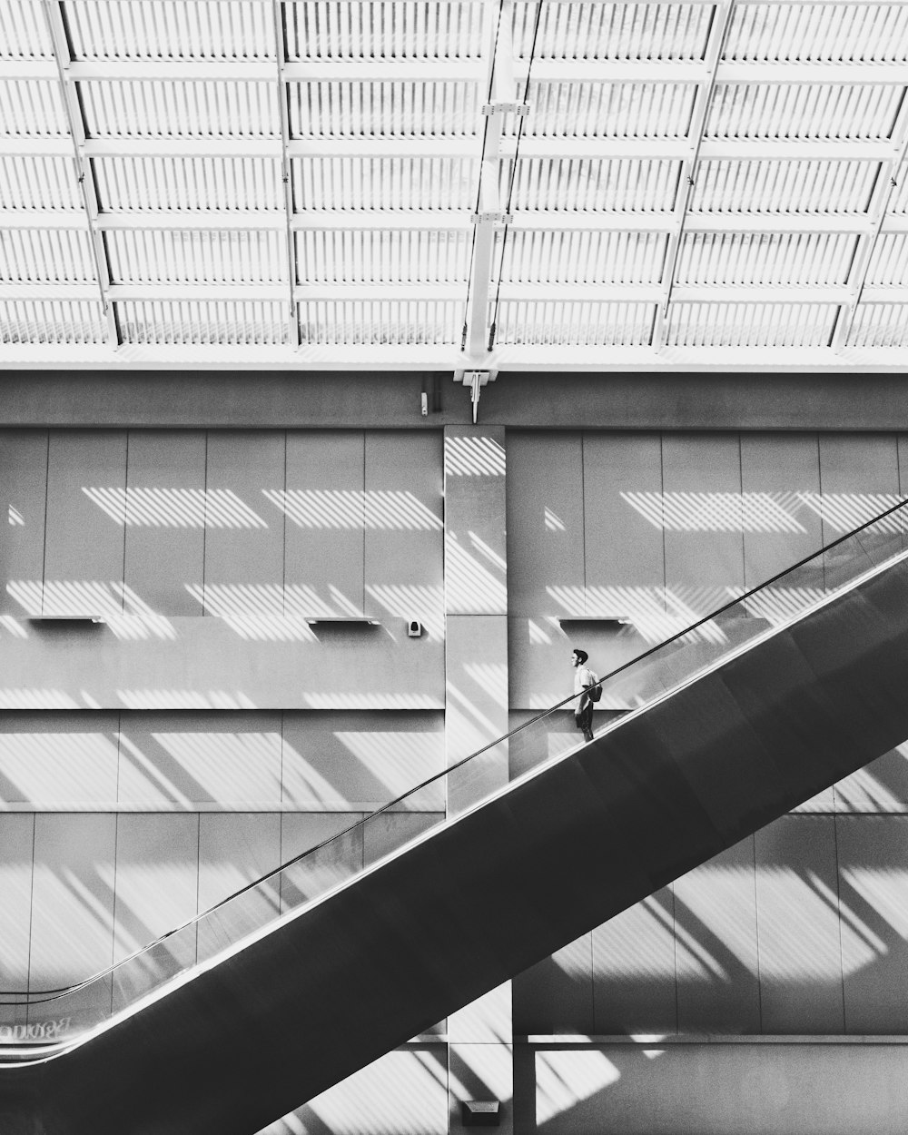 grayscale photo of man standing on escalator